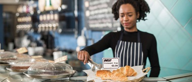 Dependienta junto a croissants con etiqueta de precio