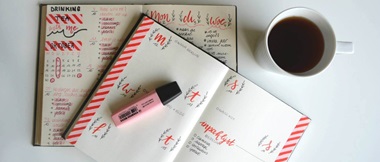 Agenda con marcador encima y taza de café