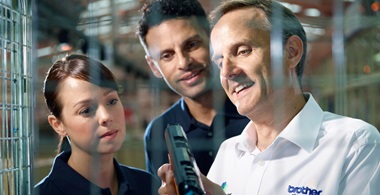 Three Brother technicians in a factory looking at a Brother toner